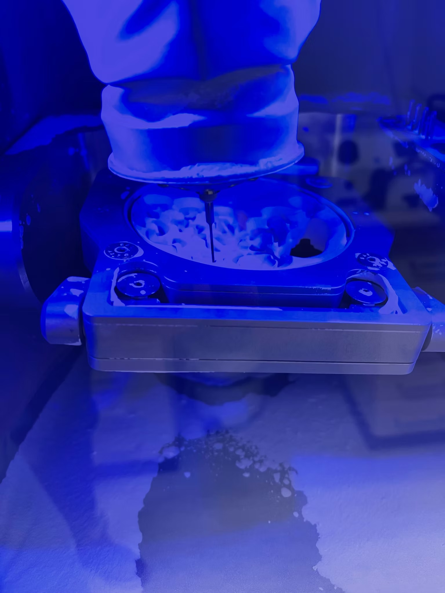 Eine Maschine unter blauem Licht bearbeitet ein Material mit einem Bohrkopf.